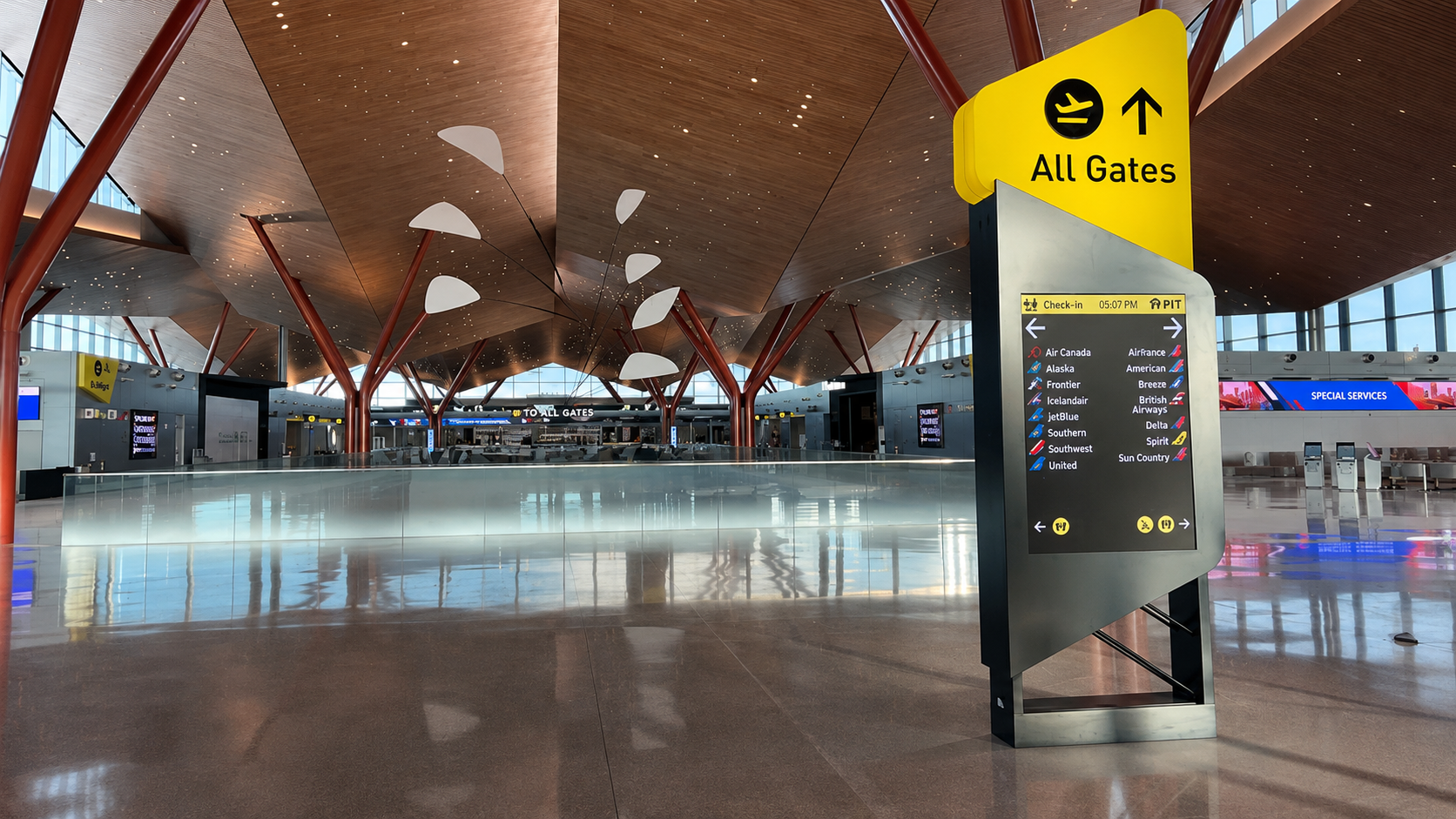 Overhead digital All Gates wayfinding display in an airport terminal above a passenger walkway