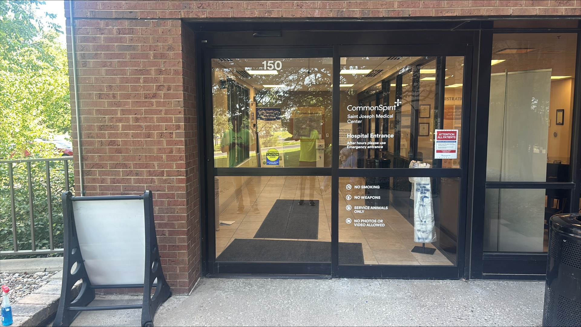Hospital entrance glass doors with CommonSpirit Saint Joseph Medical Center vinyl graphics and policy icons