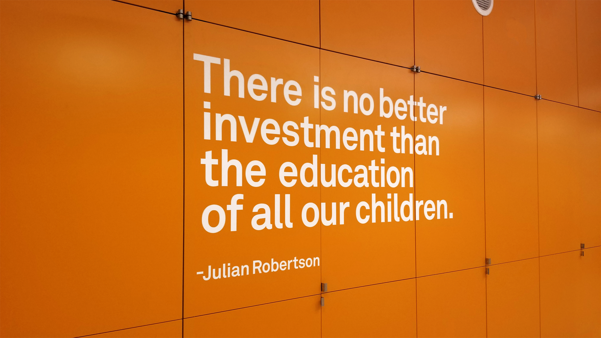 Large-scale interior wall typography carrying a quotation across an orange corridor wall