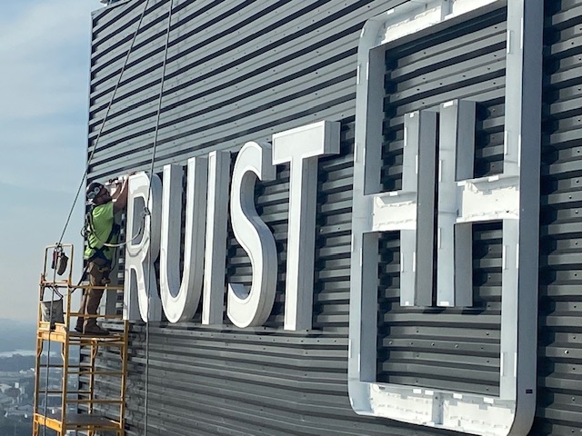 AIS installers mounting illuminated channel letters on a bank building