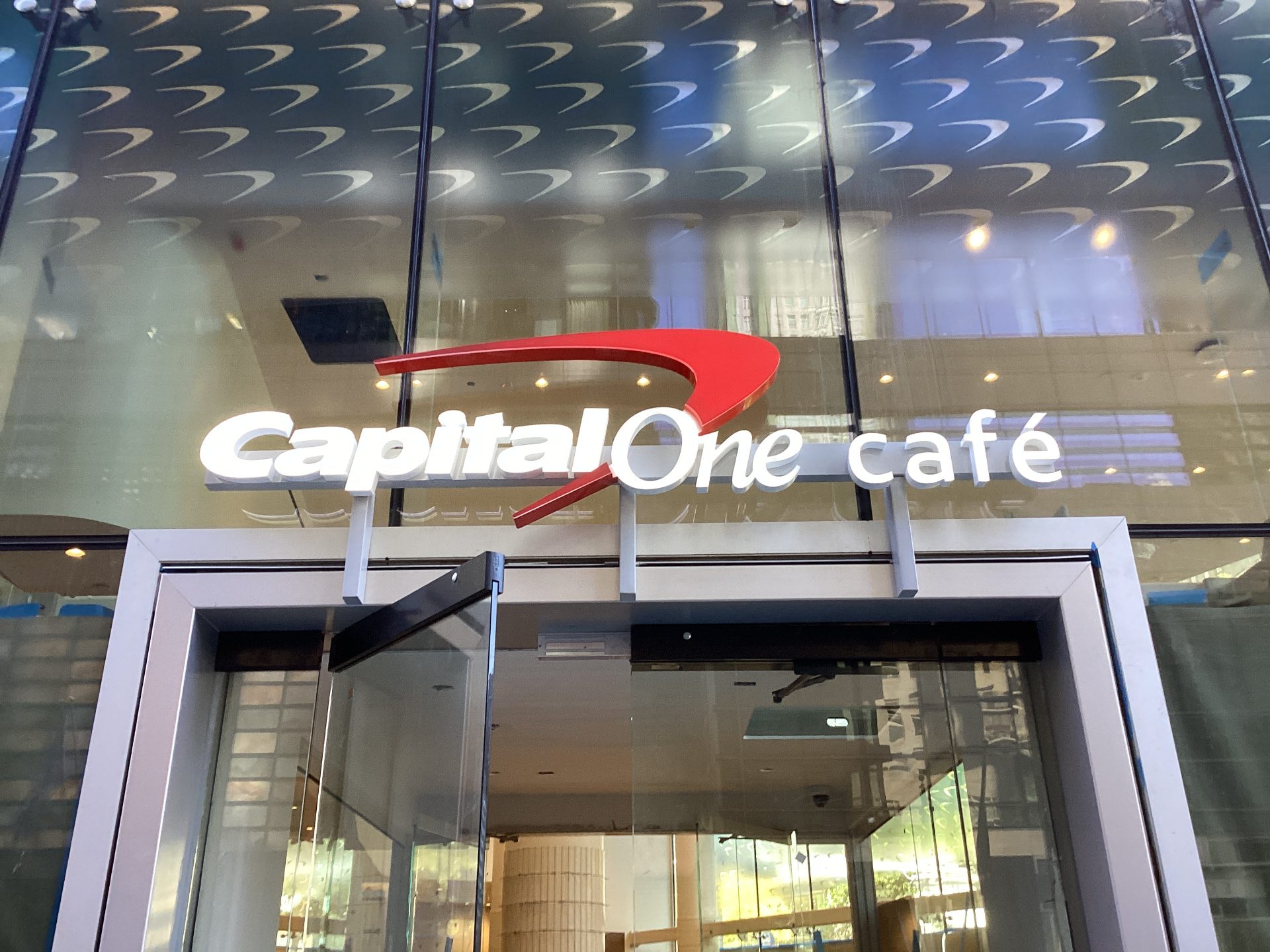 Illuminated café-format bank storefront signage above a glass entrance