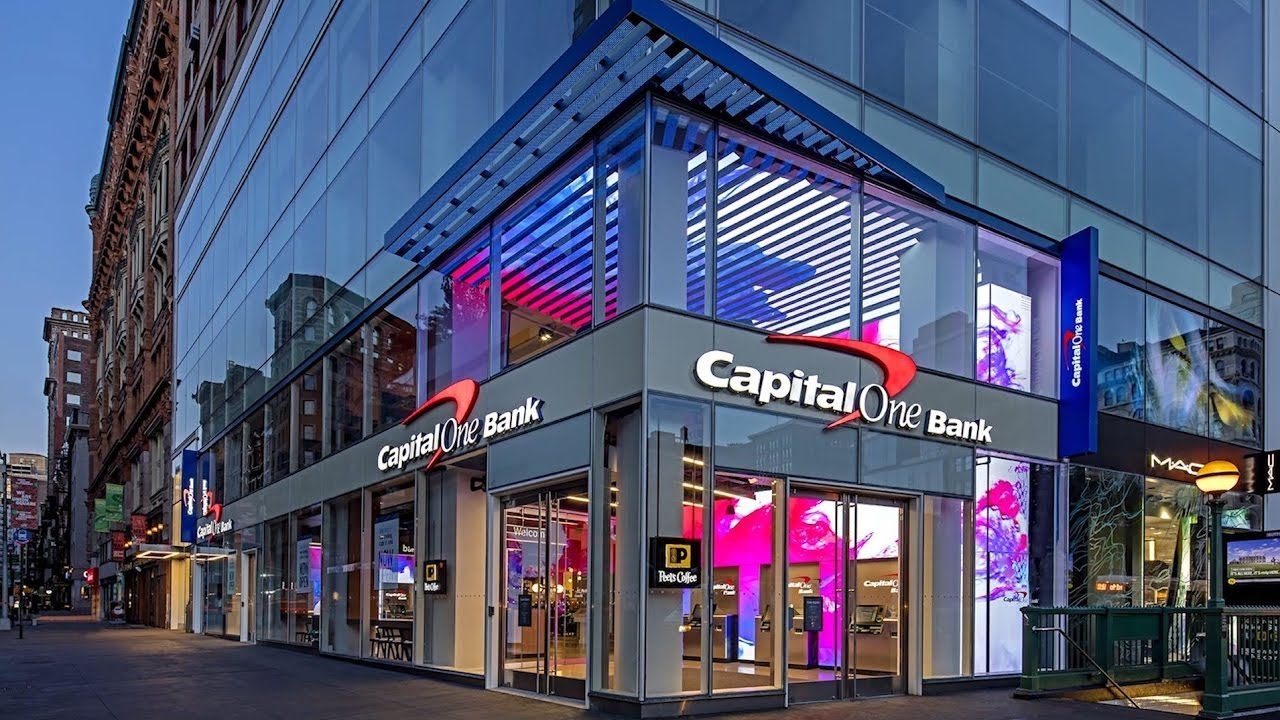 Illuminated corner bank branch storefront with exterior brand signage at dusk