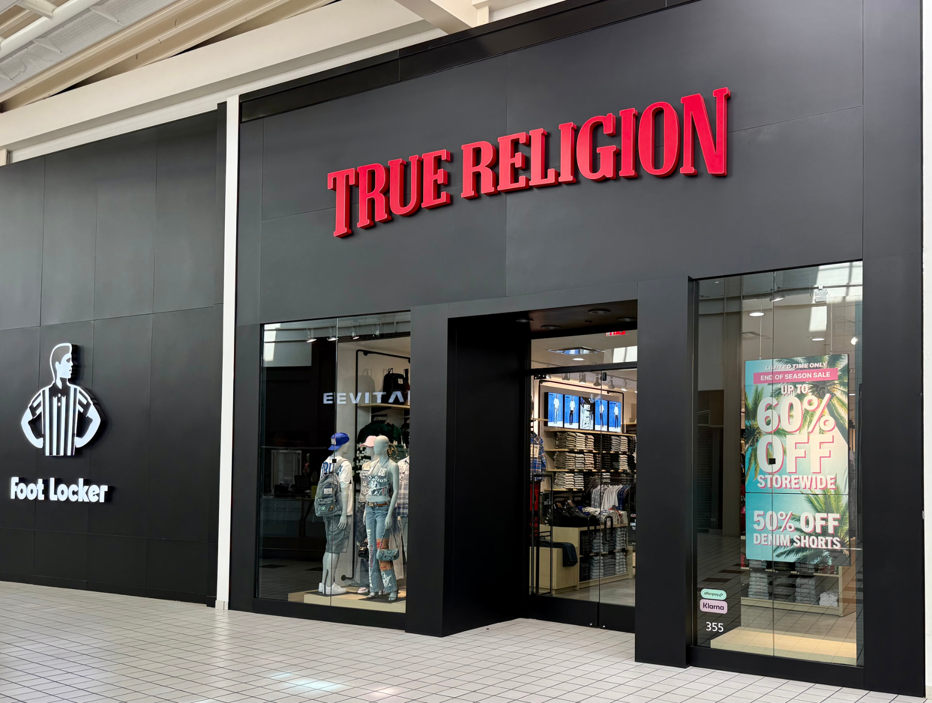 True Religion mall storefront with red illuminated channel letters on a black fascia