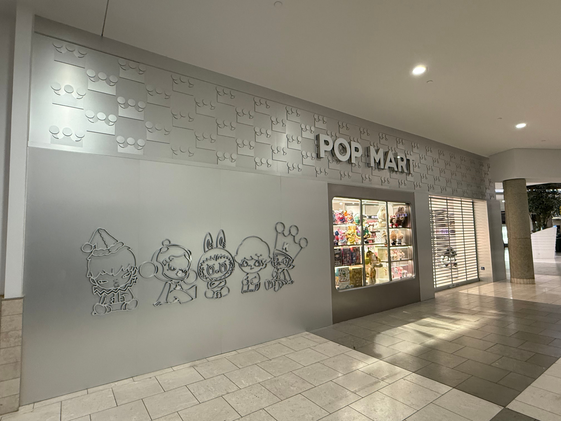 Pop Mart retail storefront with dimensional crown logo wall and character graphics